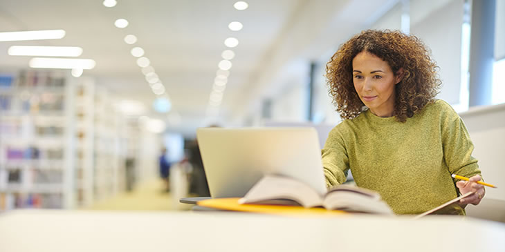 Woman in a library working on a laptop